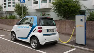 A small electric car plugged into a charging station